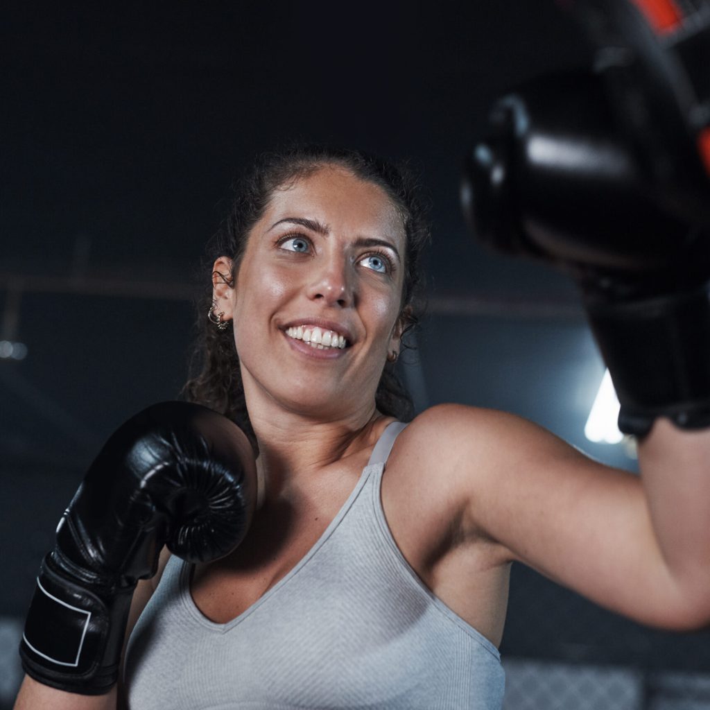 Shot of a young woman practicing with her coach at a boxing gym