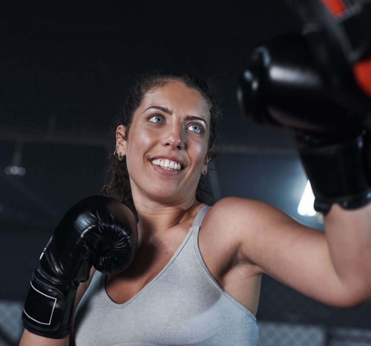 Shot of a young woman practicing with her coach at a boxing gym